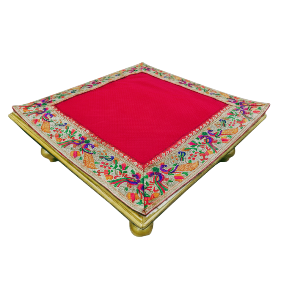 A square decorative cushion or low table featuring a vibrant red center panel and an ornate multicolored embroidered border with floral and bird motifs, set against a plain white background.